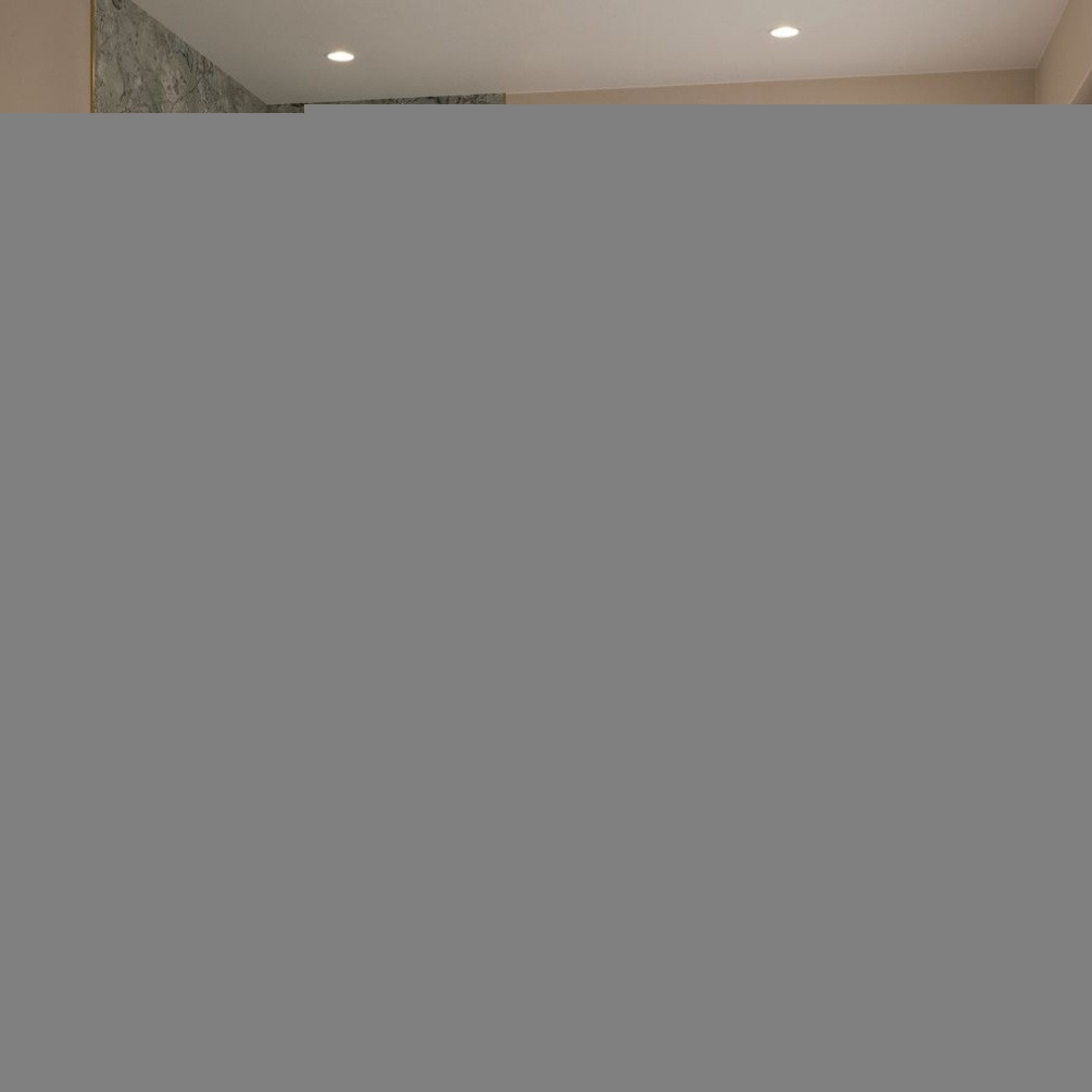 Lifestyle image of the Showerwall Laminate Classico Verde 2440mm x 900mm Square Cut Hydrocore Wall Panel - SW92 installed within a walk in shower enclosure, in a bathroom with wall hung vanity unit and round mirror